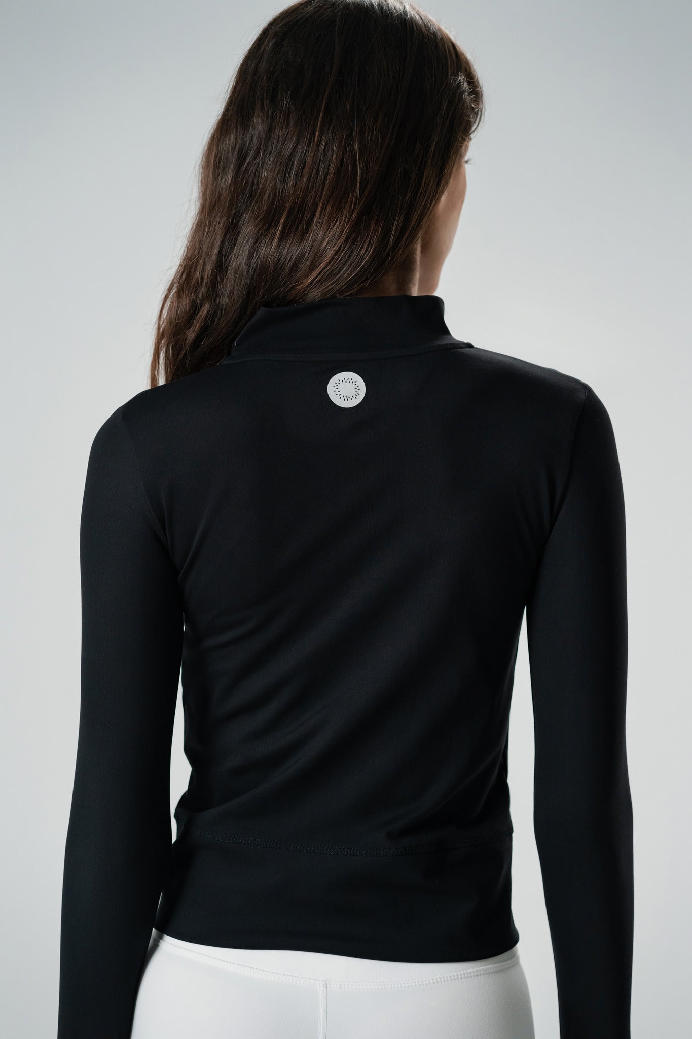 A woman wearing a black zip-up sports jacket  back close up