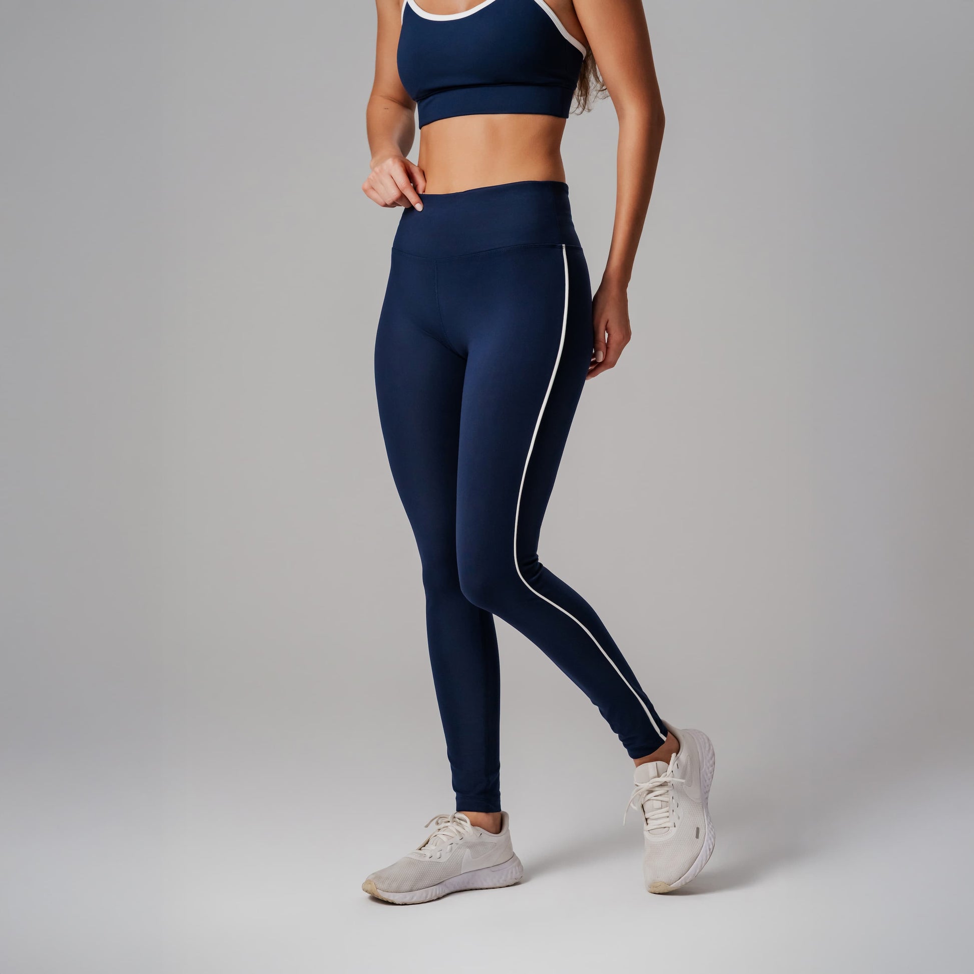 Person wearing navy leggings with a white stripe on a gray background