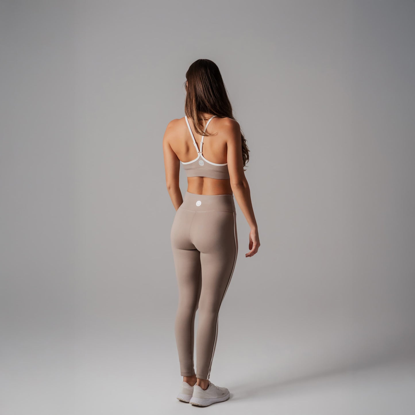 Woman wearing a sports bra and leggings on a gray background