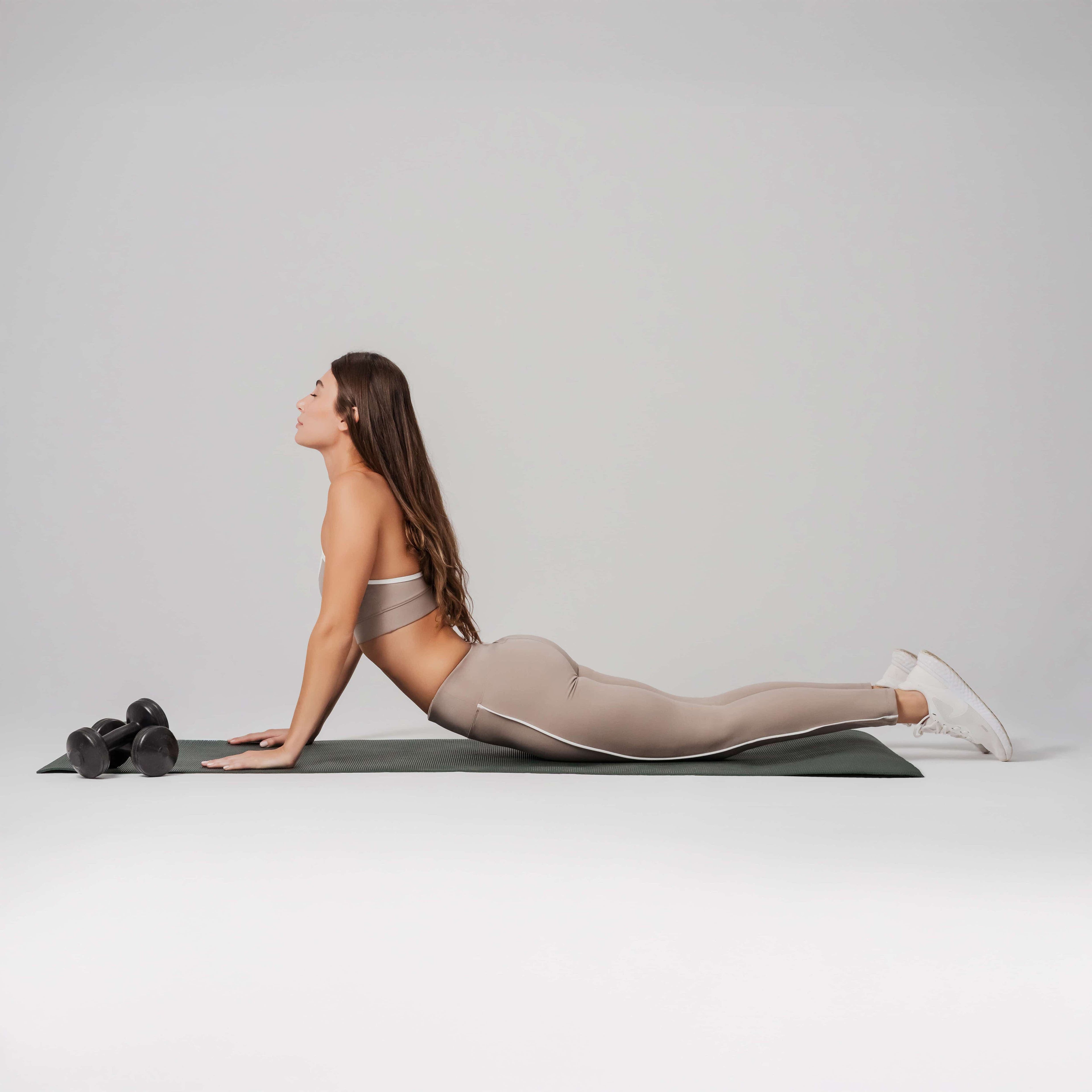 Woman performing a yoga pose on a mat with a neutral background