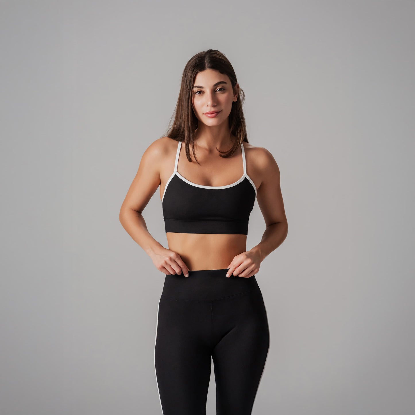 Woman wearing a black sports bra and leggings on a gray background