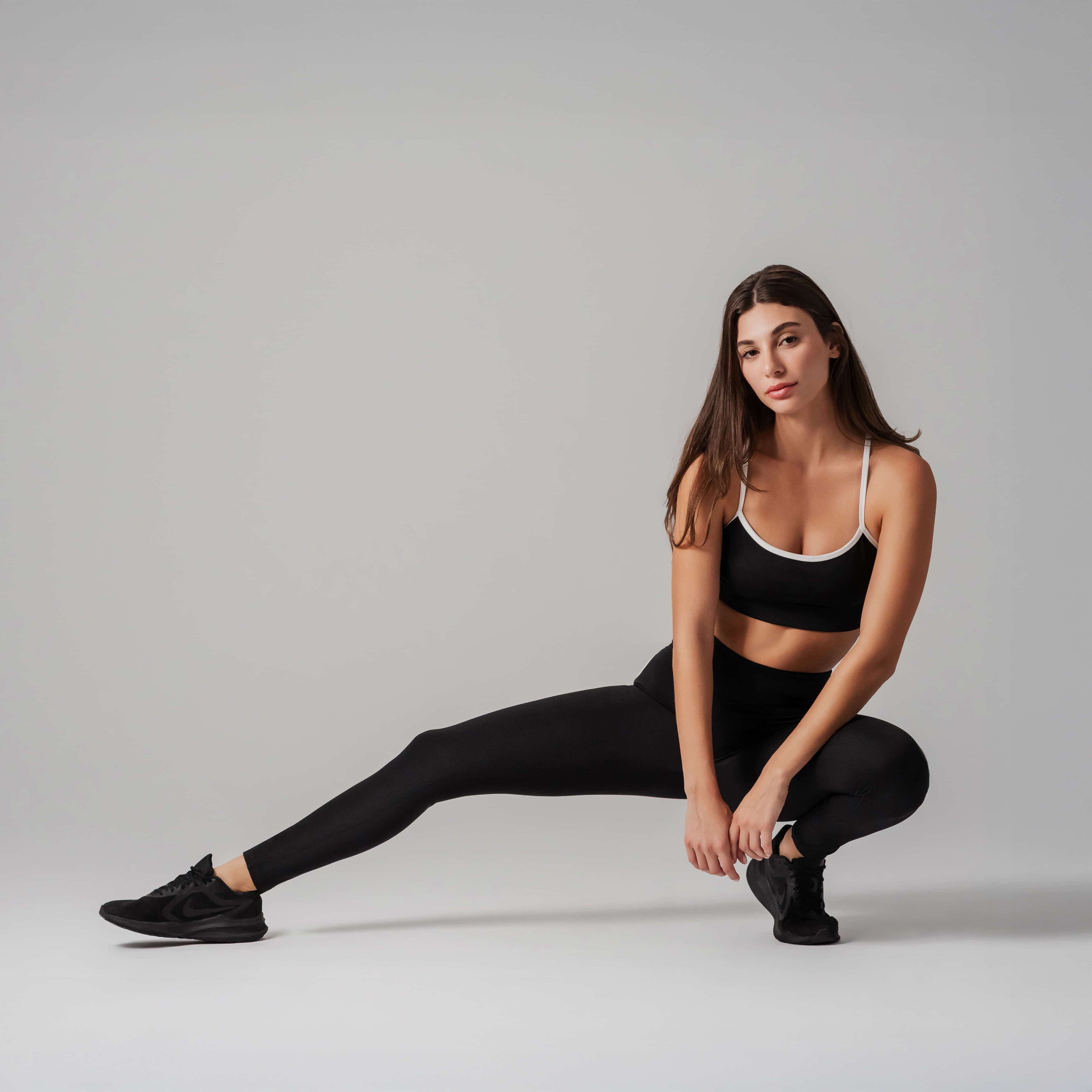 Woman in black athletic wear posing against a gray background