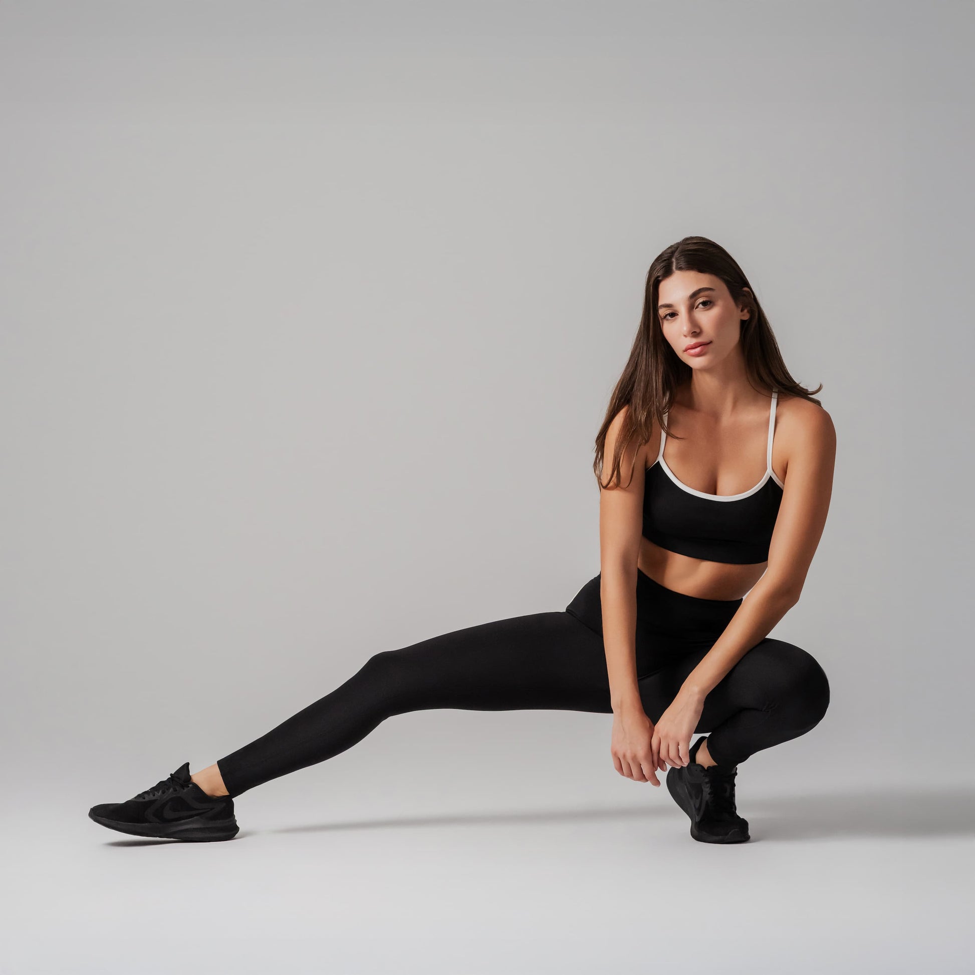 Woman in black athletic wear posing on a gray background