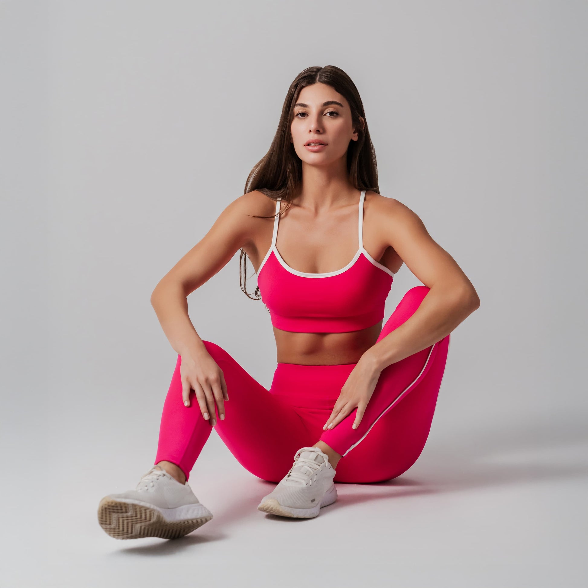 Woman in pink athletic outfit posing on a plain background