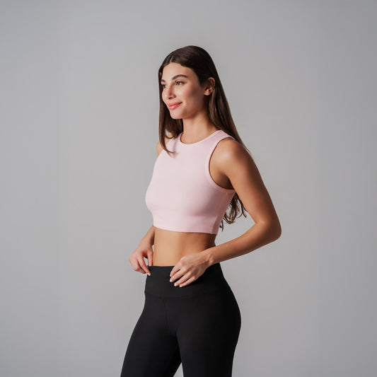 Woman wearing a pink cropped tank and black leggings on a gray background
