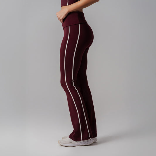 Burgundy pants with white stripes worn by a person on a gray background