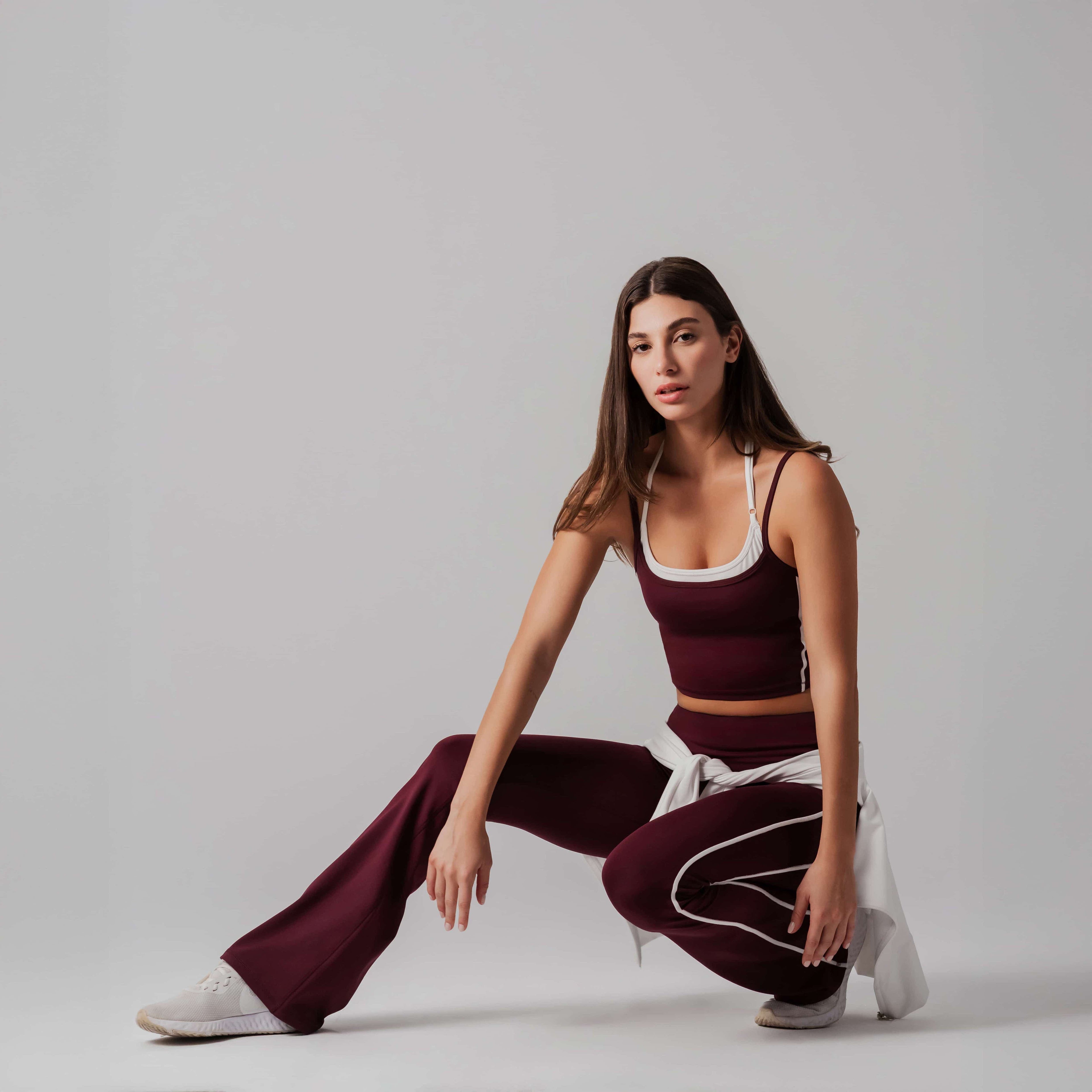 Woman in burgundy athletic outfit posing on a gray background