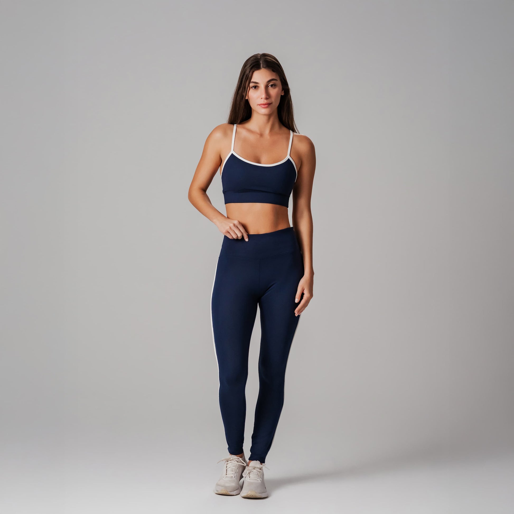 Woman wearing a navy sports bra and leggings set on a gray background