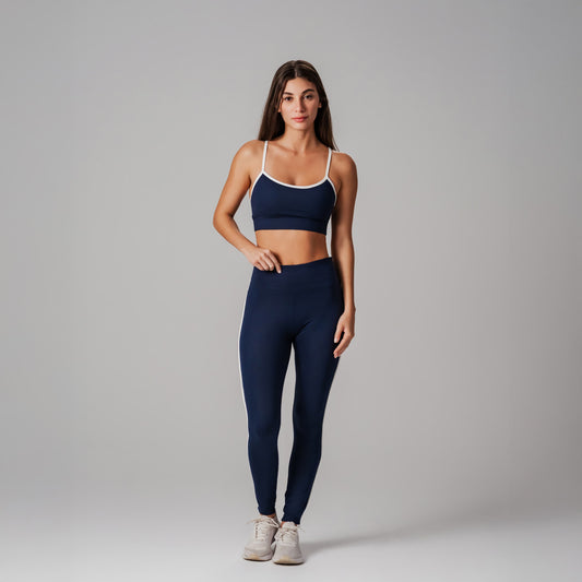 Woman wearing a navy sports bra and leggings set on a gray background