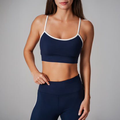 Woman wearing a navy sports bra and leggings on a gray background