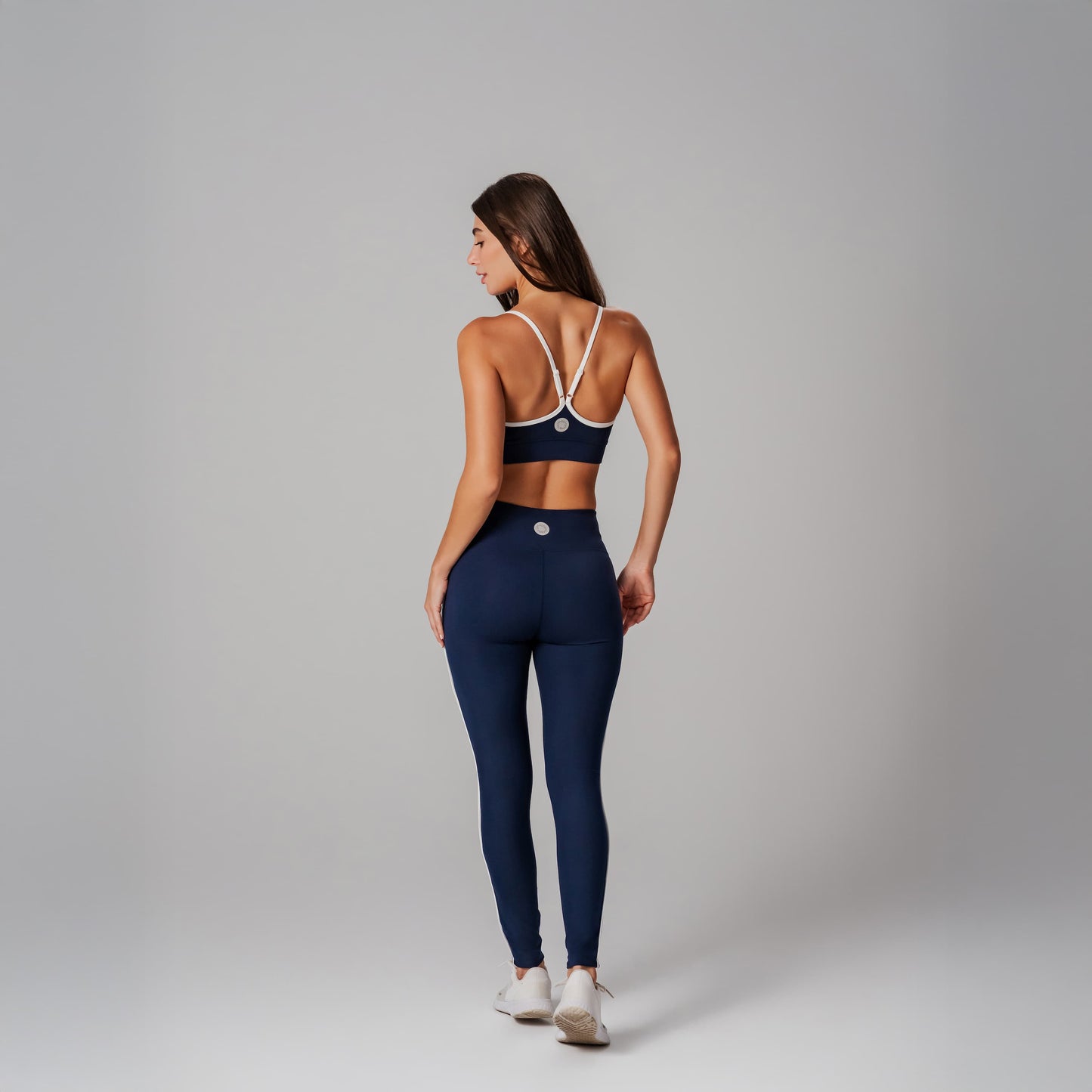 Woman wearing a navy sports bra and leggings set on a gray background