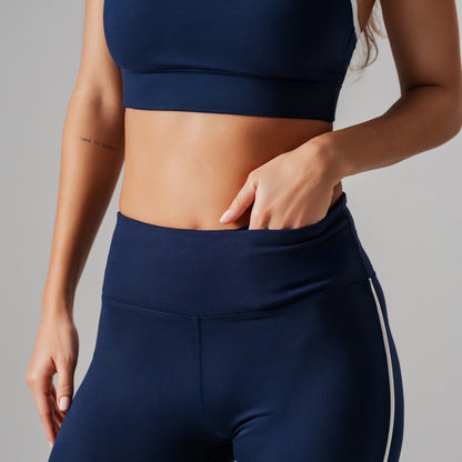 Person wearing navy blue athletic top and leggings on a gray background