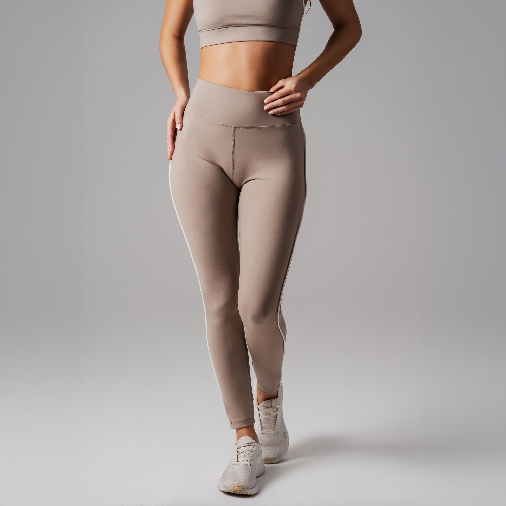 Person wearing beige leggings and a matching top on a plain background