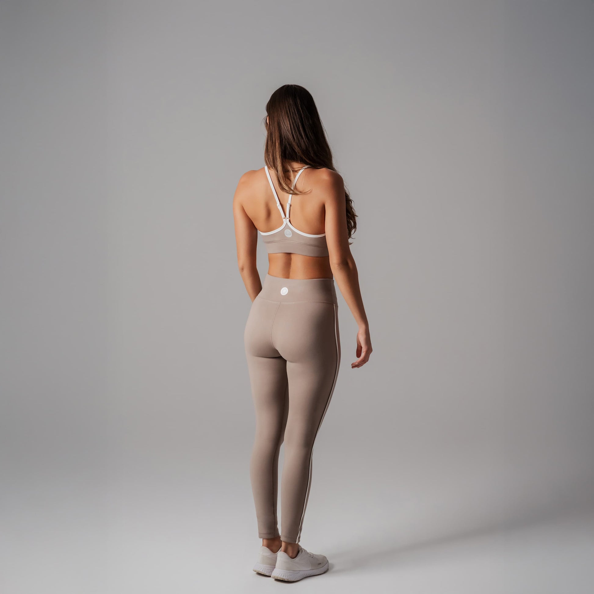 Woman wearing a sports bra and leggings on a gray background
