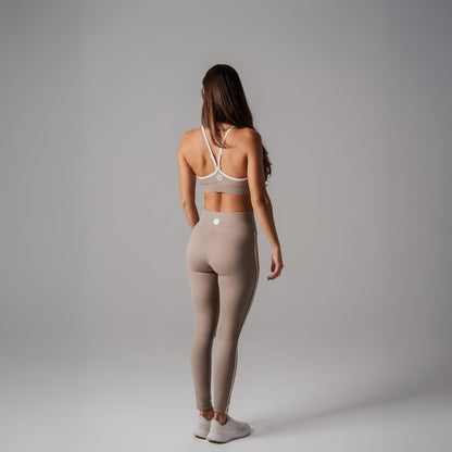 Woman wearing a sports bra and leggings on a gray background