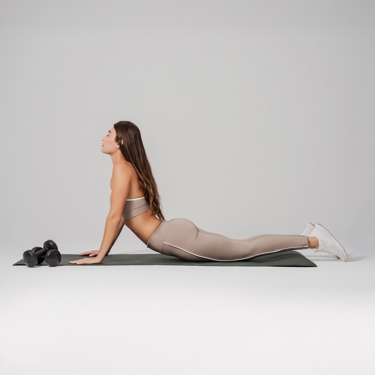 Woman in a yoga pose on a mat with a gray background