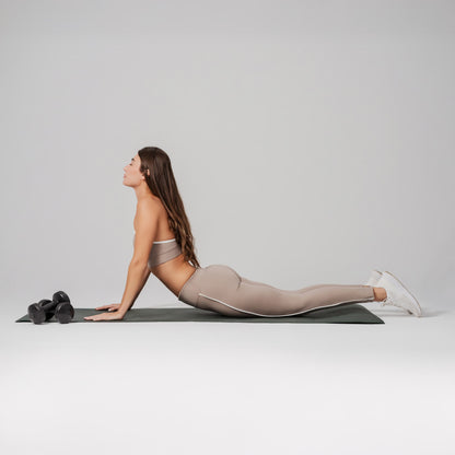 Woman in a yoga pose on a mat with a gray background
