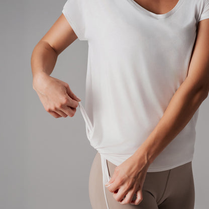 Person wearing a white t-shirt and beige pants against a gray background