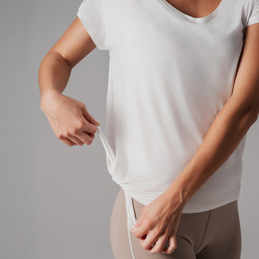 Person wearing a white t-shirt and beige pants against a gray background