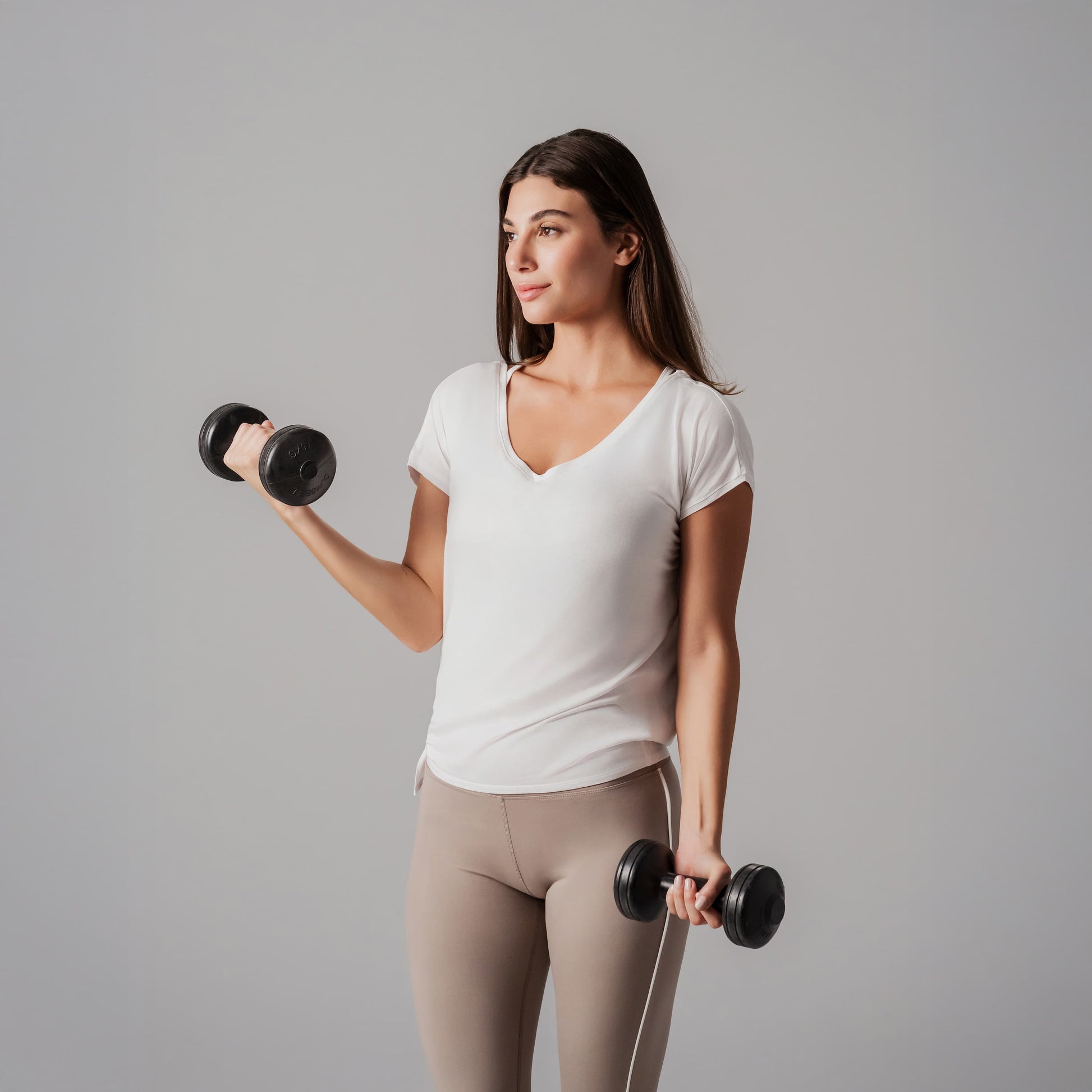 Woman exercising with dumbbells against a gray background