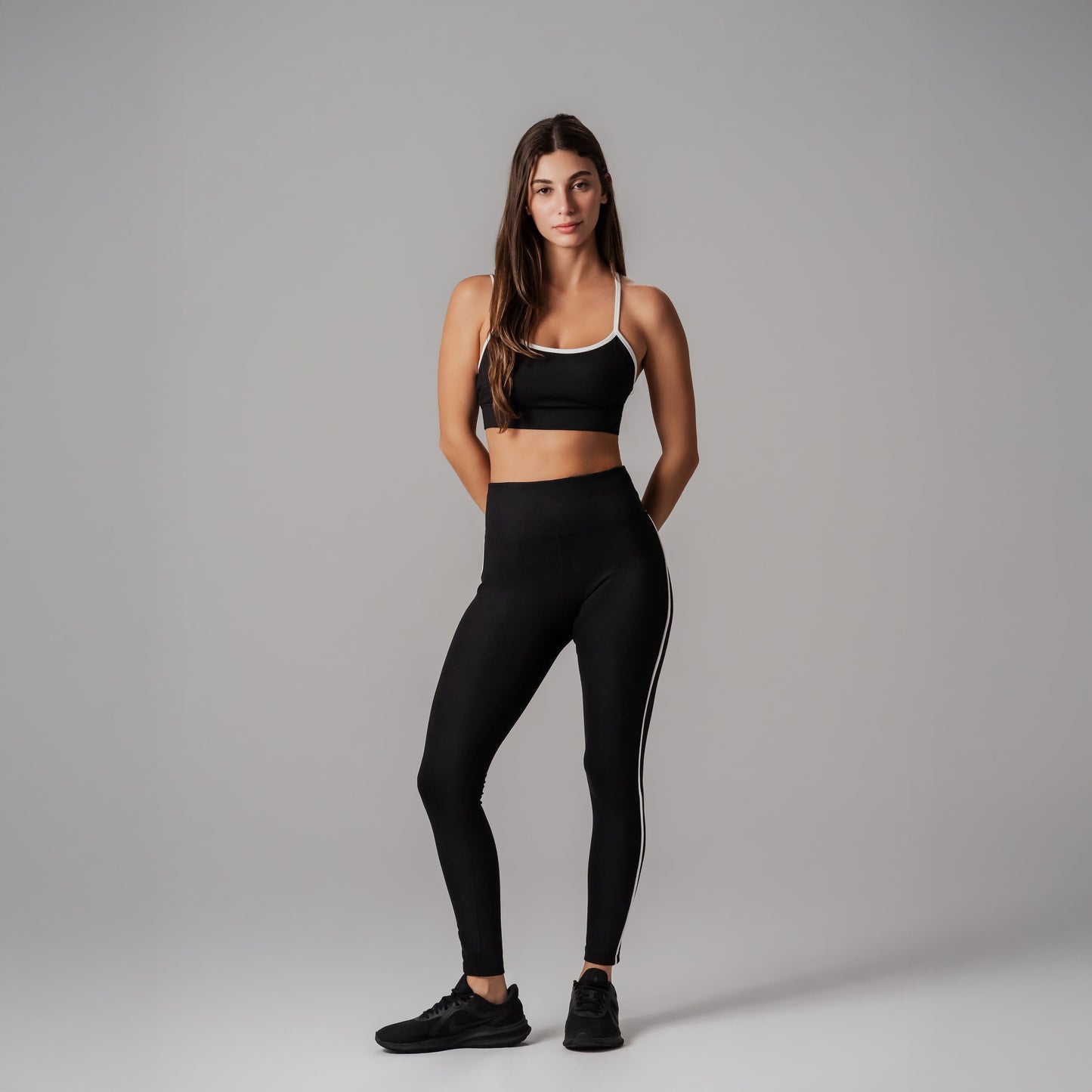 Woman wearing a black sports bra and leggings on a gray background