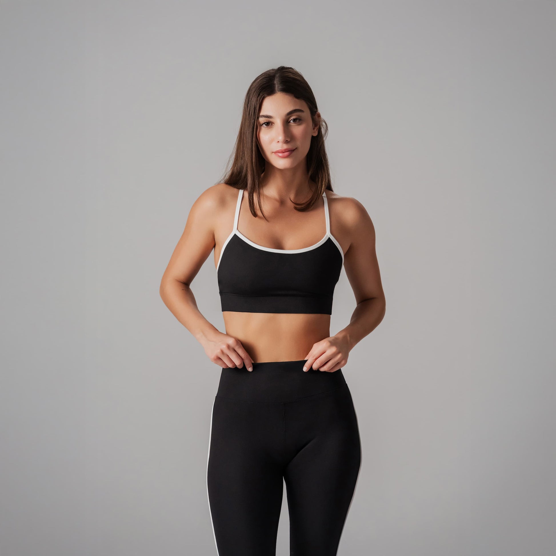 Woman wearing a black sports bra and leggings on a gray background
