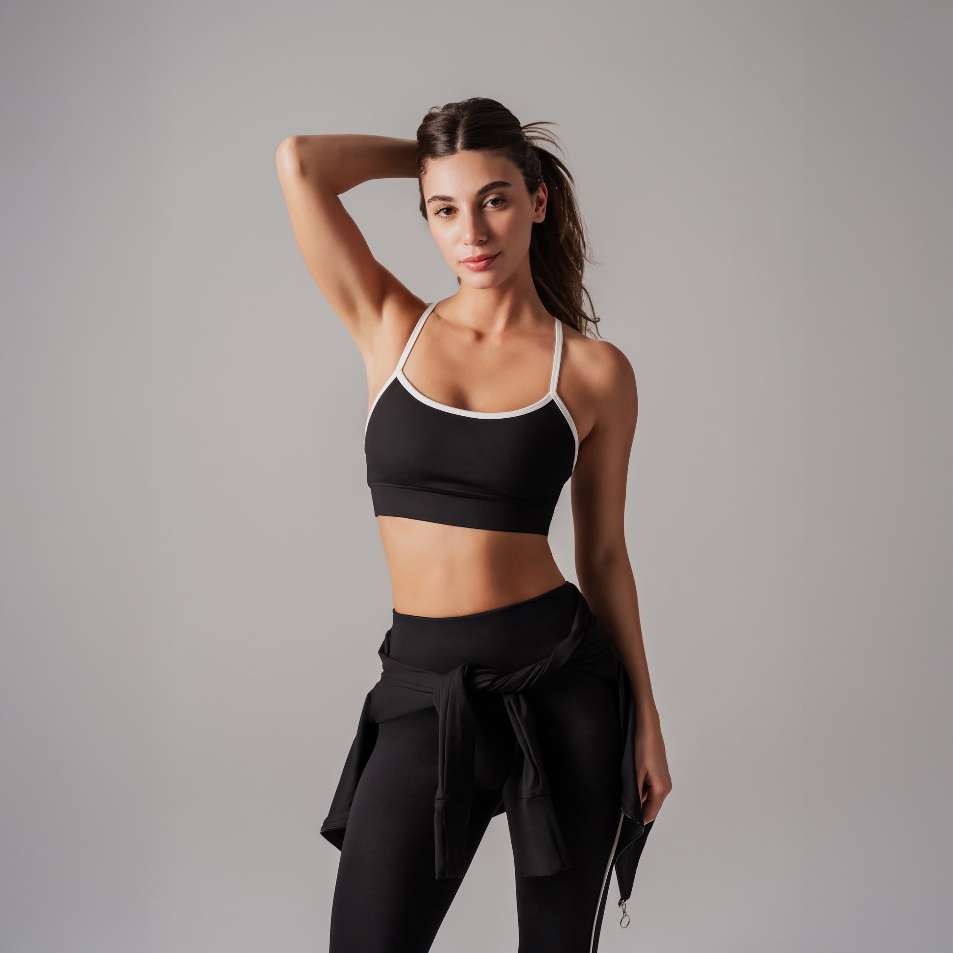 Woman wearing a black sports bra and leggings on a gray background
