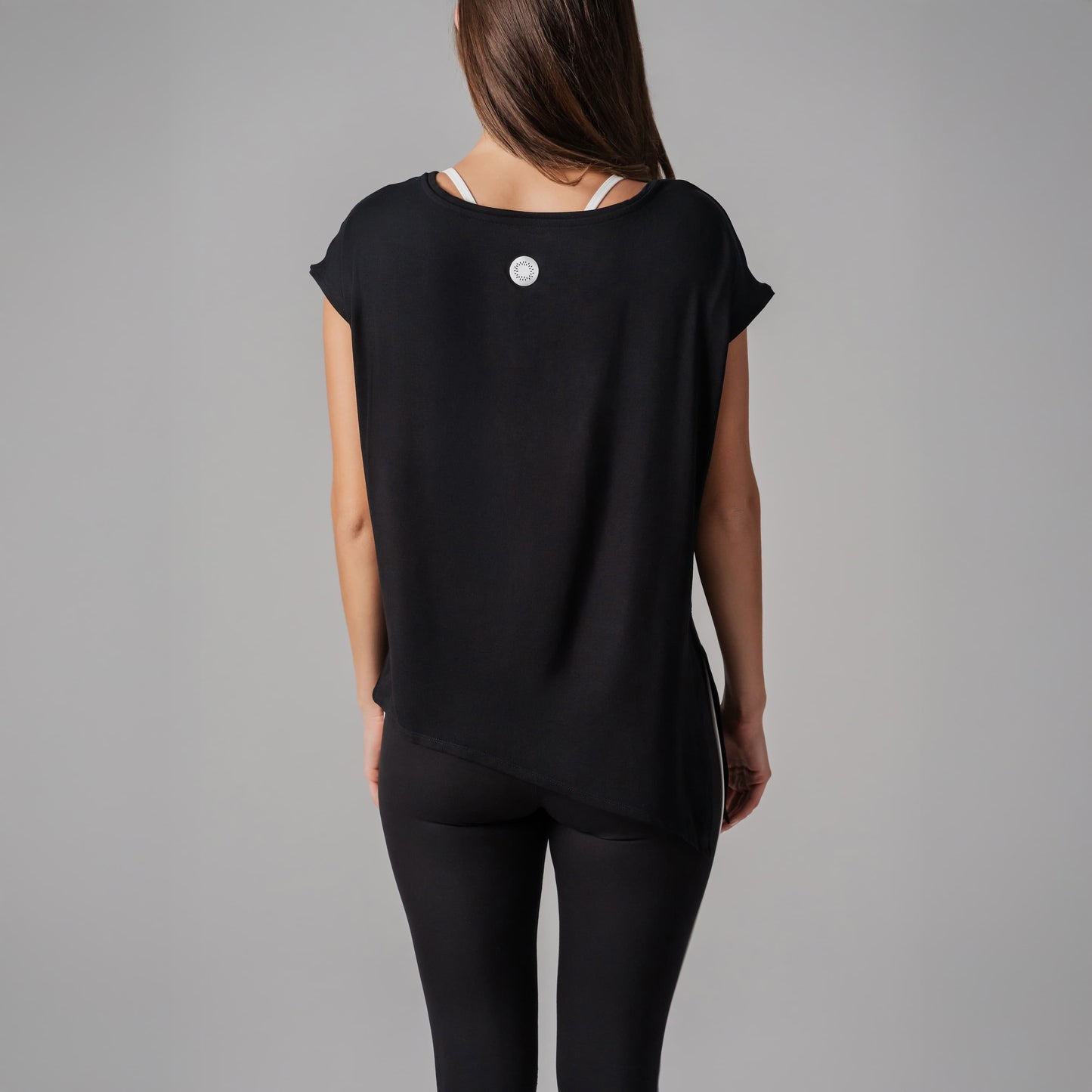 Person wearing a black top with a small white logo on a gray background