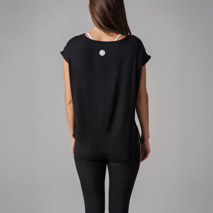 Person wearing a black top with a small white logo on a gray background