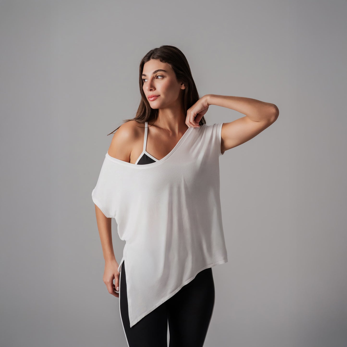 A girl wearing a white top and black pants against a gray background