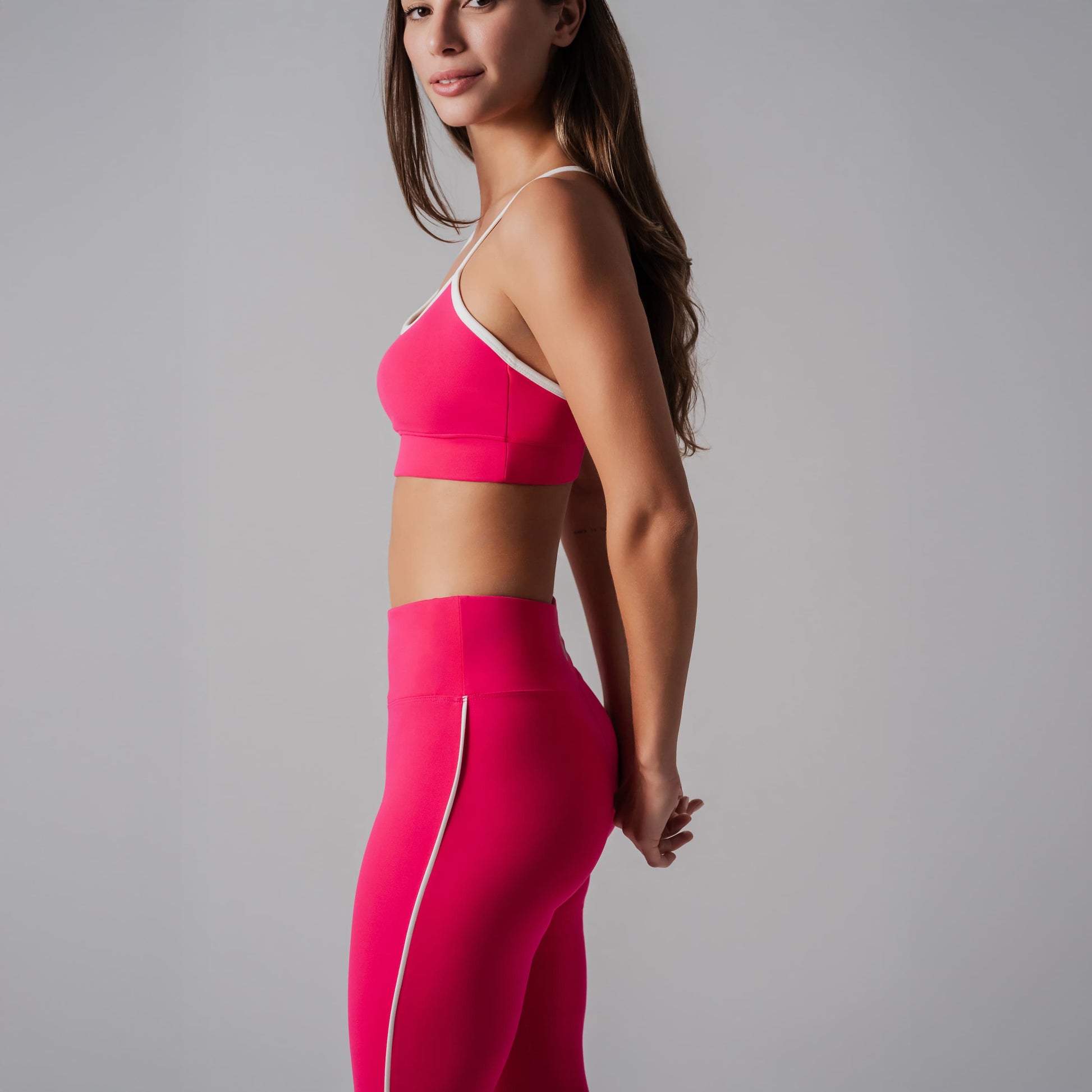 Woman wearing a pink sports bra and leggings on a gray background