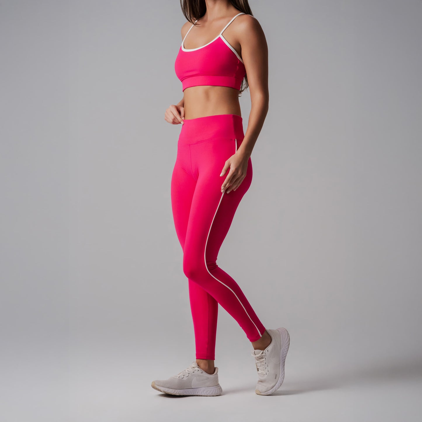 Person wearing a bright fuchsia athletic outfit with white stripes on a gray background