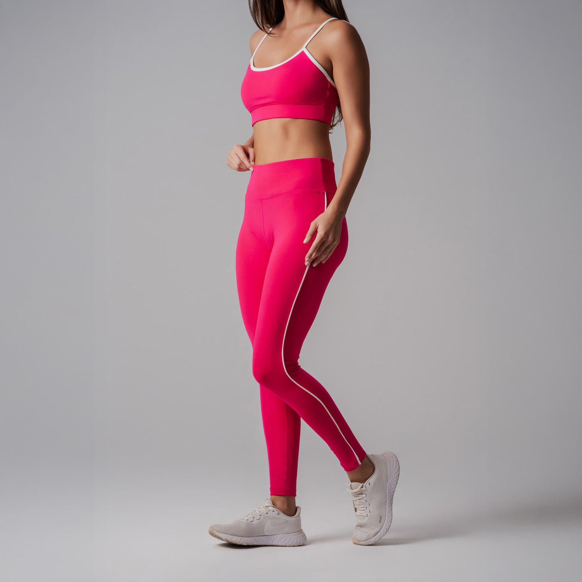 Person wearing a bright fuchsia athletic outfit with white stripes on a gray background