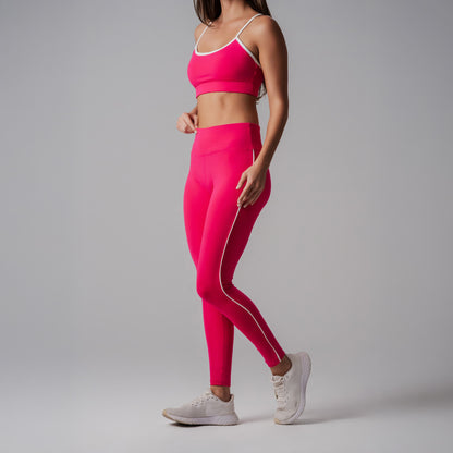 Person wearing a bright fuchsia athletic outfit with white stripes on a gray background