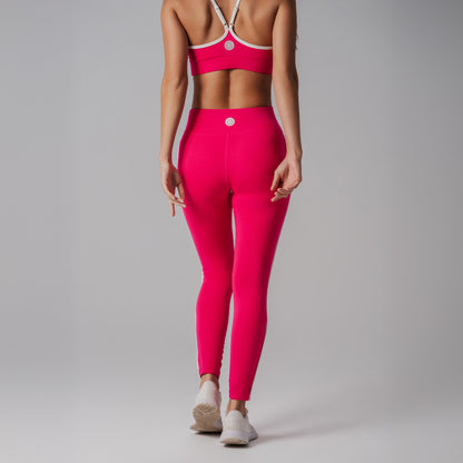 Person wearing bright fuchsia athletic leggings and sports bra on a gray background