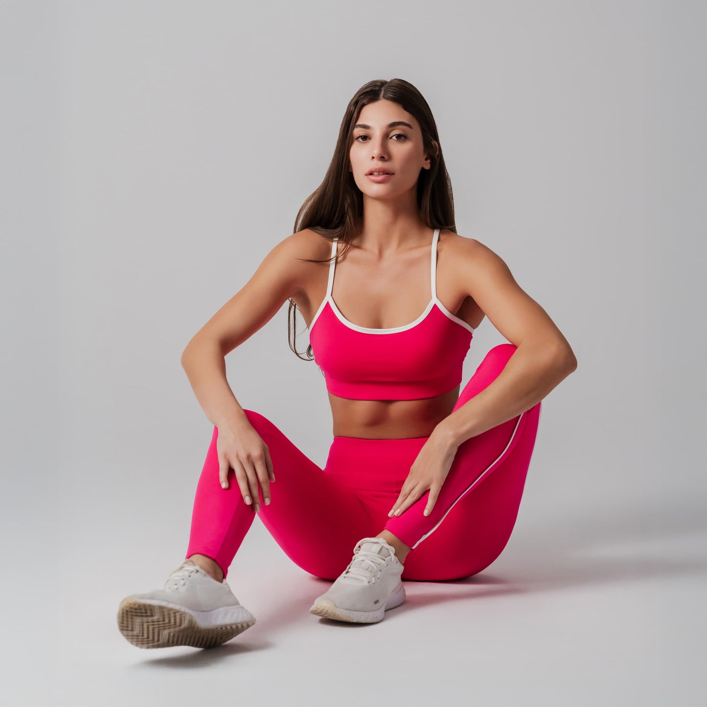 Woman in pink athletic outfit posing on a plain background