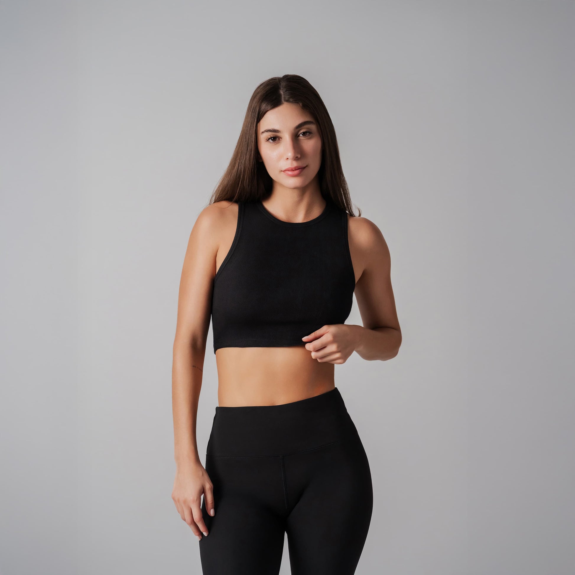 Woman wearing a black sports bra and leggings on a gray background