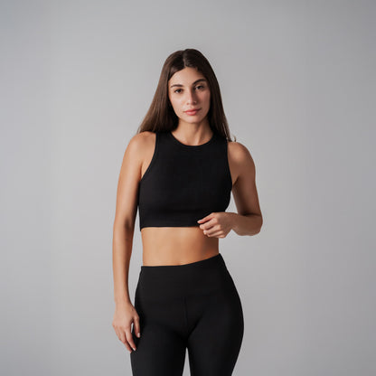 Woman wearing a black sports bra and leggings on a gray background