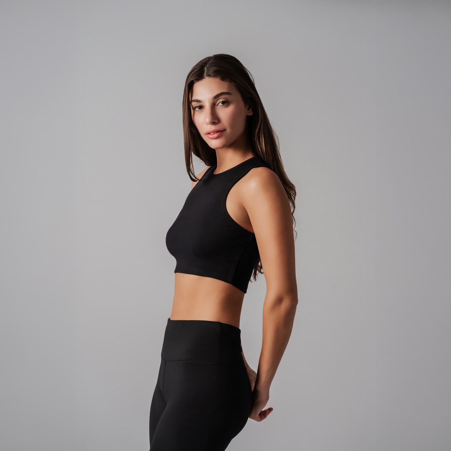 Woman wearing a black athletic outfit against a gray background