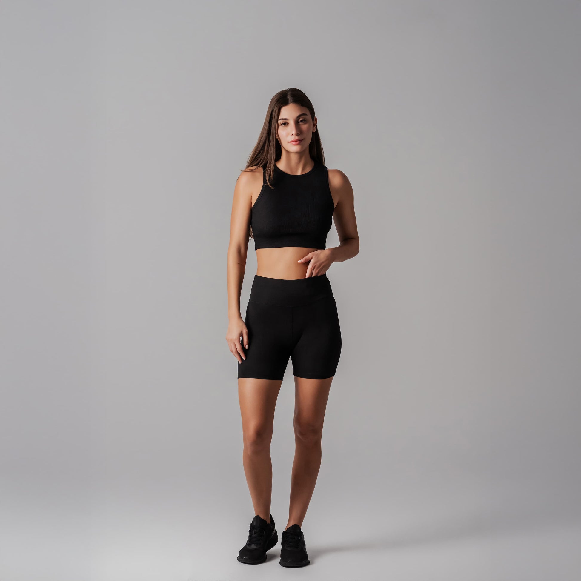 Woman wearing a black athletic outfit on a gray background