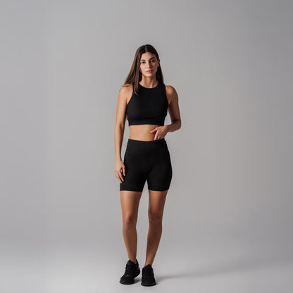 Woman wearing a black athletic outfit on a gray background