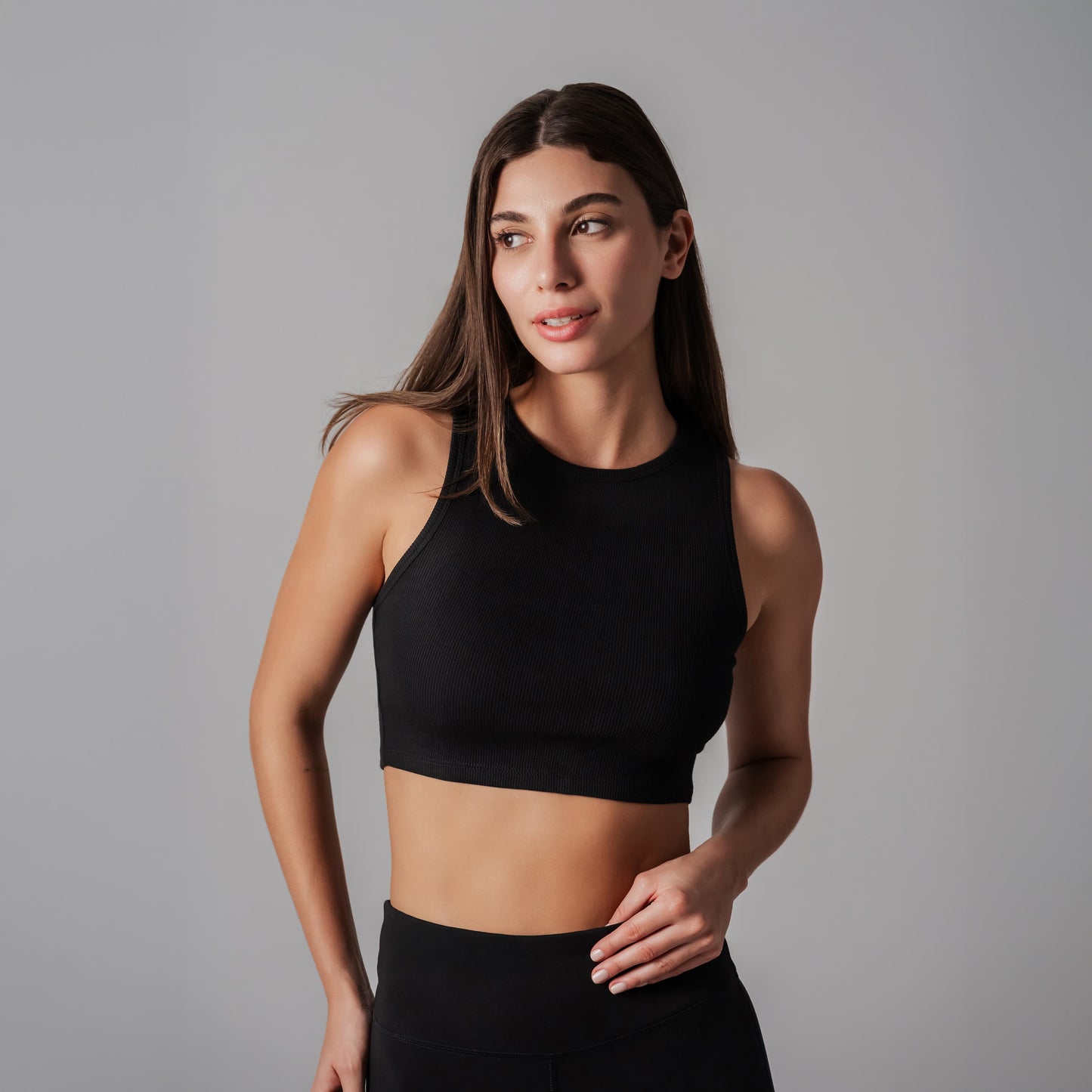 Woman wearing a black sports bra and leggings against a gray background