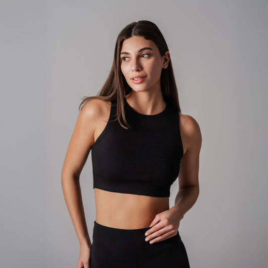 Woman wearing a black sports bra and leggings against a gray background