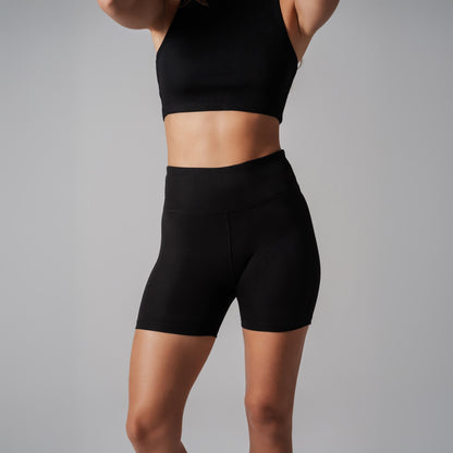 Person wearing black athletic shorts and top on a gray background