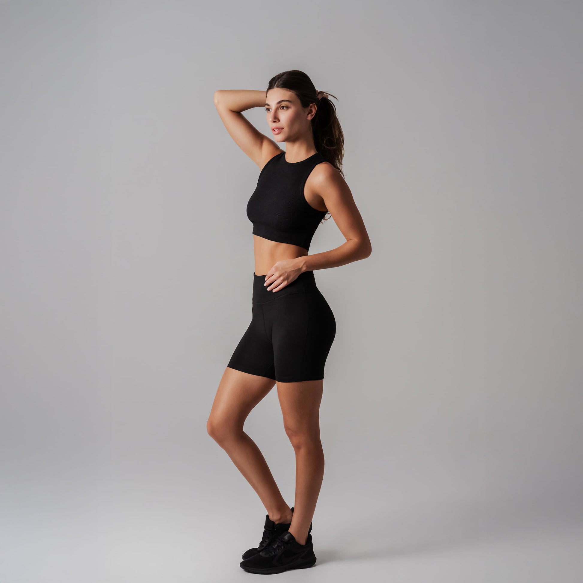 Woman wearing a black athletic outfit on a gray background
