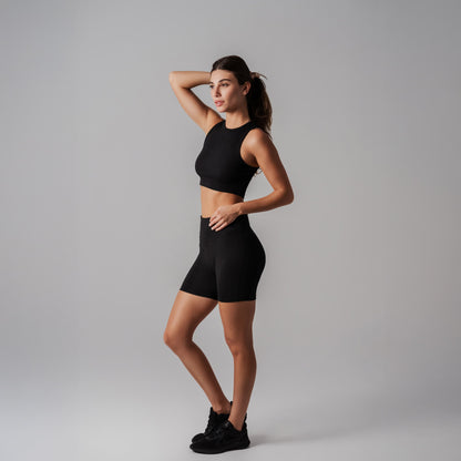 Woman wearing a black athletic outfit on a gray background