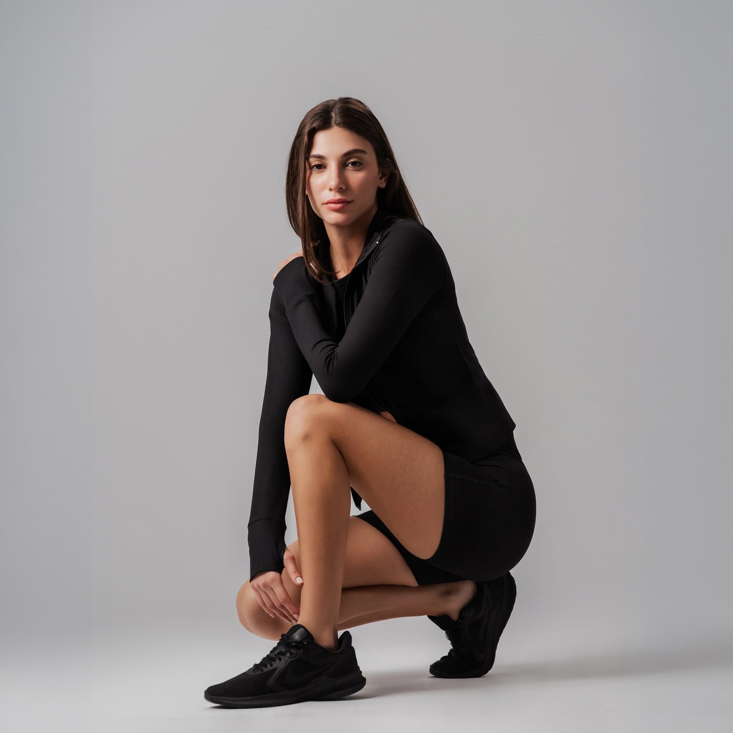 Woman in black outfit posing on a gray background