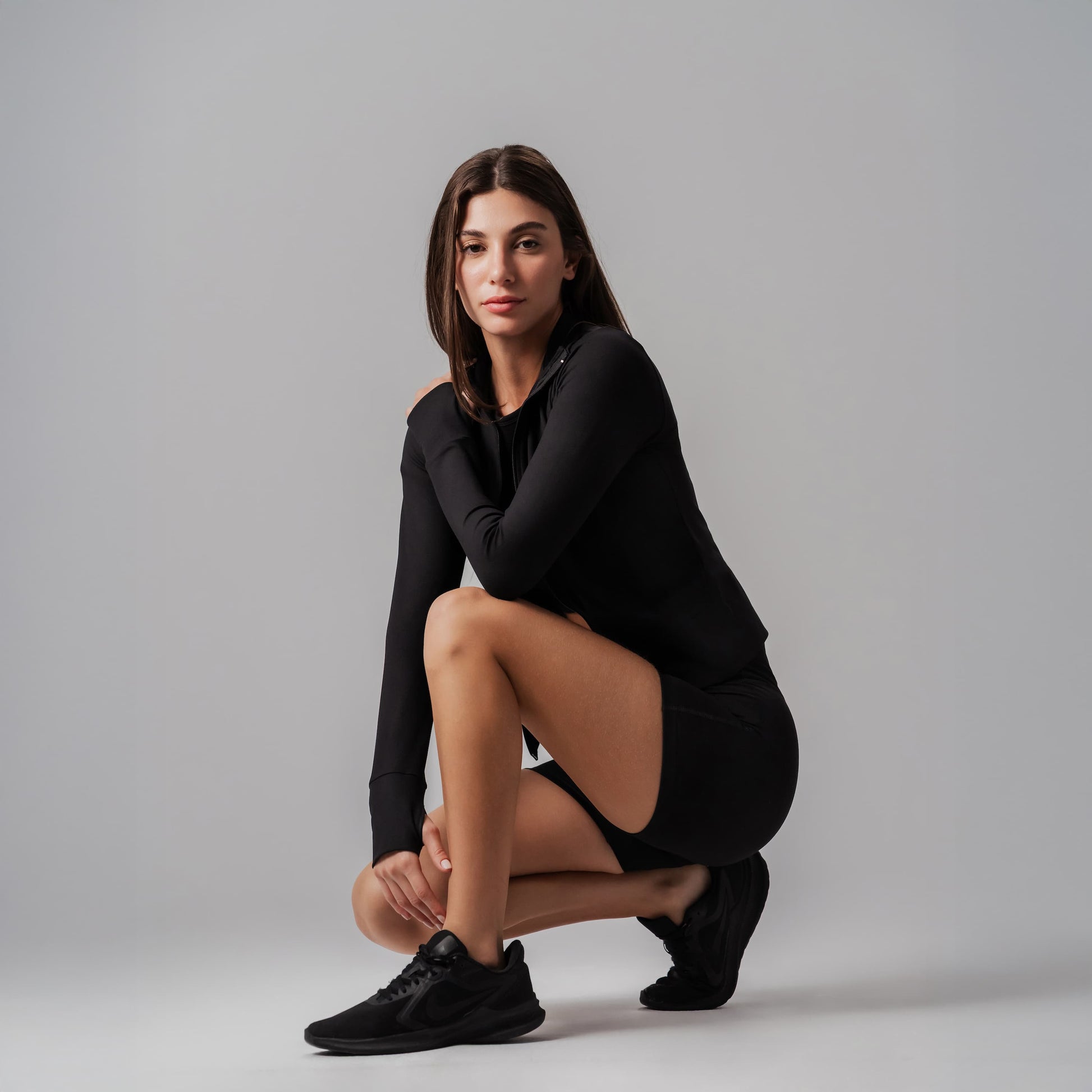 Woman in black outfit posing on a gray background