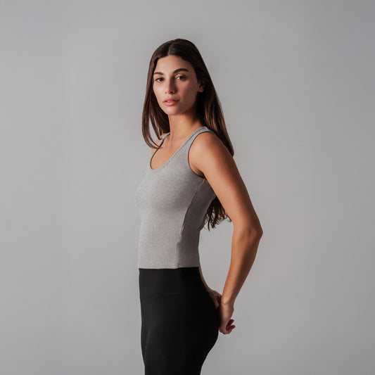 Woman wearing a gray tank top and black leggings against a gray background