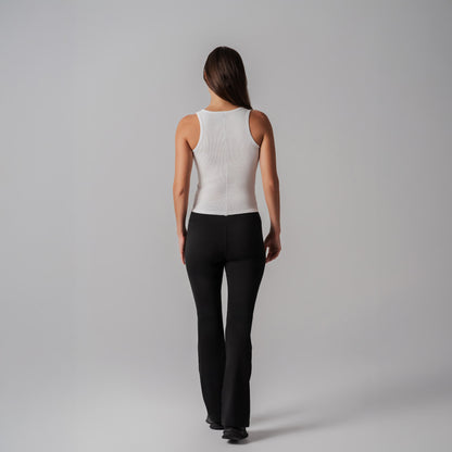 Person wearing a white sleeveless tank and black pants on a gray background